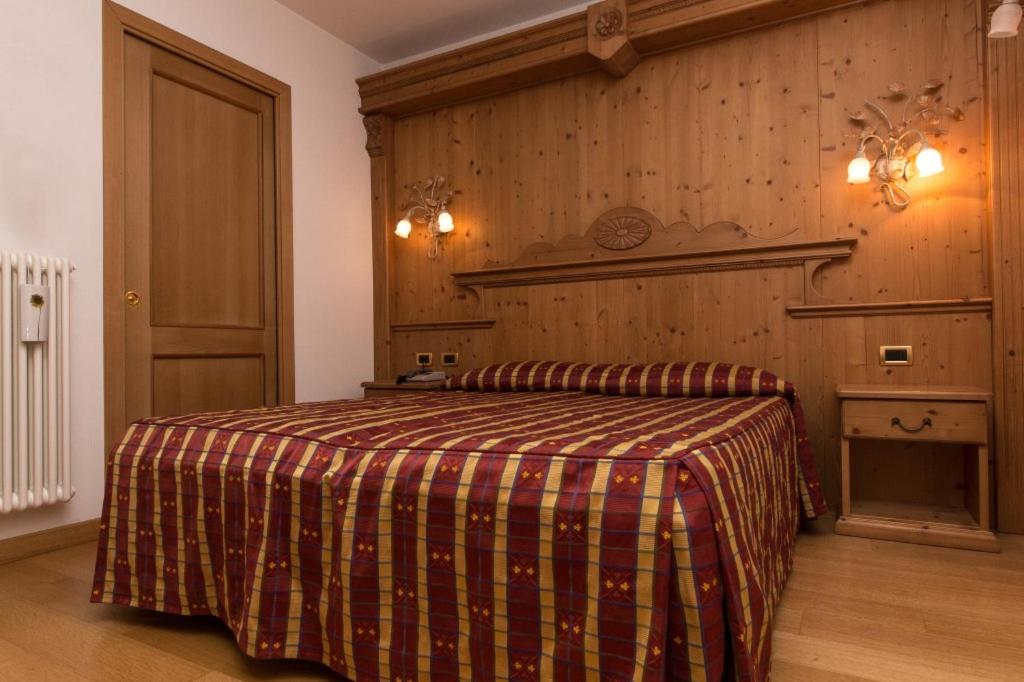 a bedroom with a bed with a plaid blanket on it at Hotel Alpi - Asiago in Asiago