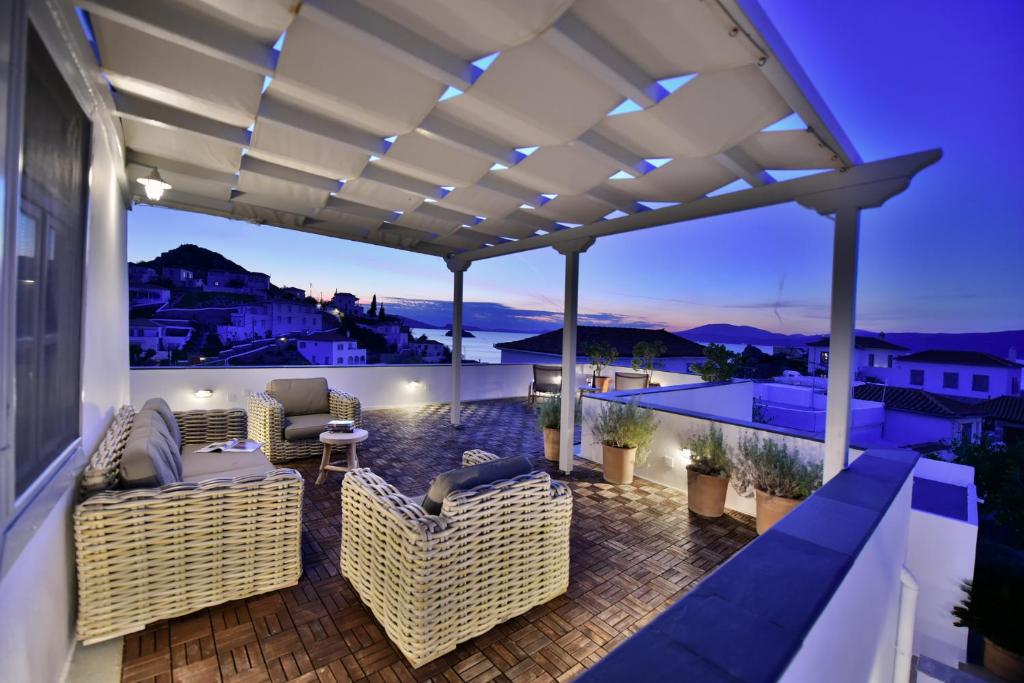 a patio with wicker chairs and a pergola at night at Villa Loukia in Hydra