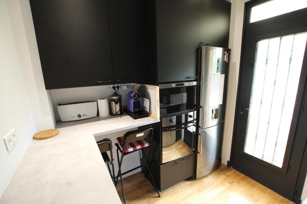 cocina con armarios negros y nevera de acero inoxidable en Cosy 2 bedroom - F3 - Apartment - 5 min Metro 5, en Romainville