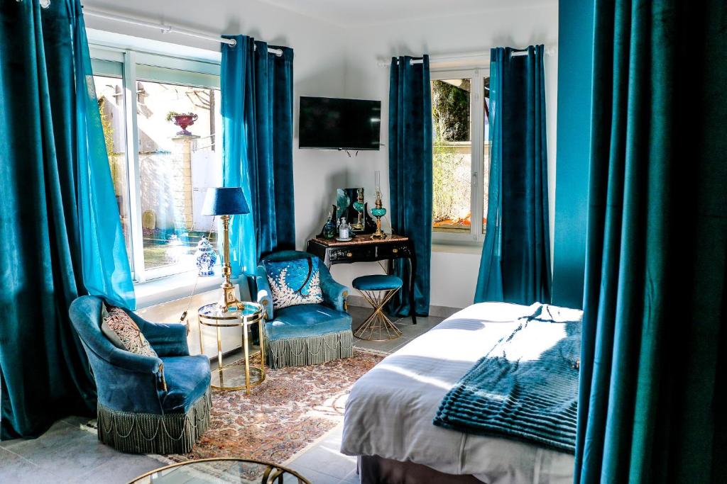sypialnia z niebieskimi zasłonami, łóżkiem i biurkiem w obiekcie Chez fabrice w mieście Dun-sur-Auron