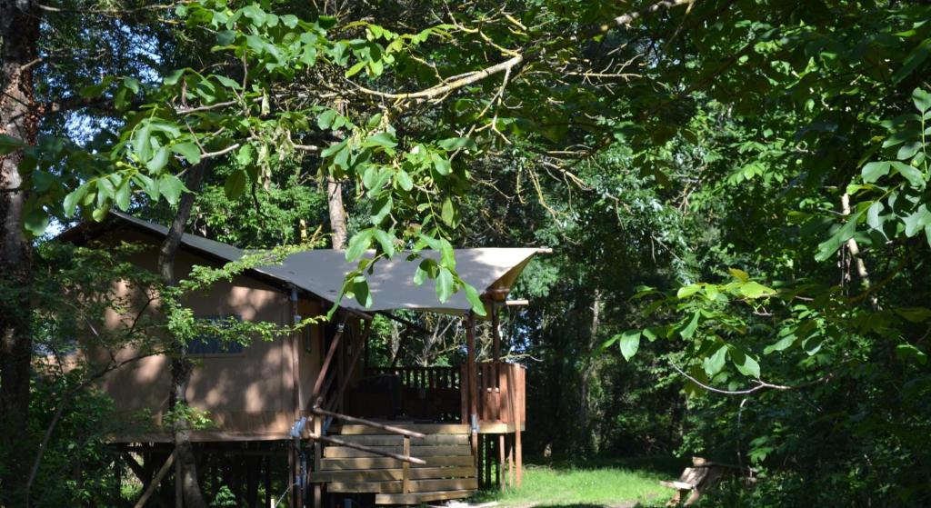 une cabane dans les arbres avec un parasol dans les bois dans l'établissement Les lodges du Moulin, à Saint-Laurent