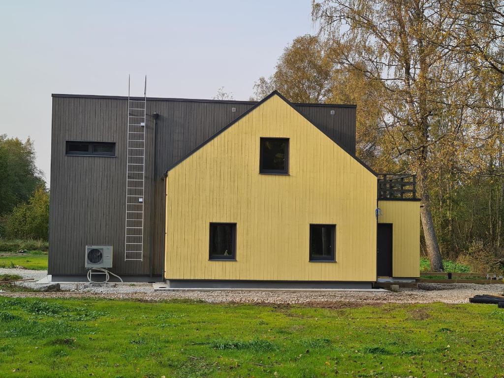 ein gelbes Haus mit schwarzem Dach in der Unterkunft Sonda puhkemaja in Sonda