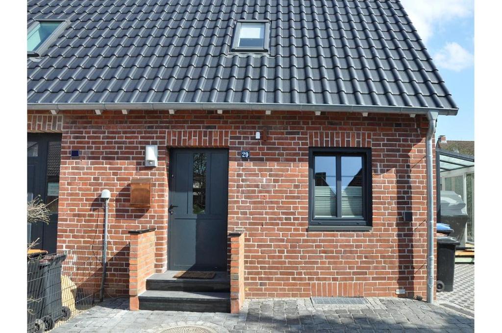 une maison en briques avec un toit noir et une porte dans l'établissement Königsberger Straße Ferienhaus Königsberger Straße, à Heiligenhafen