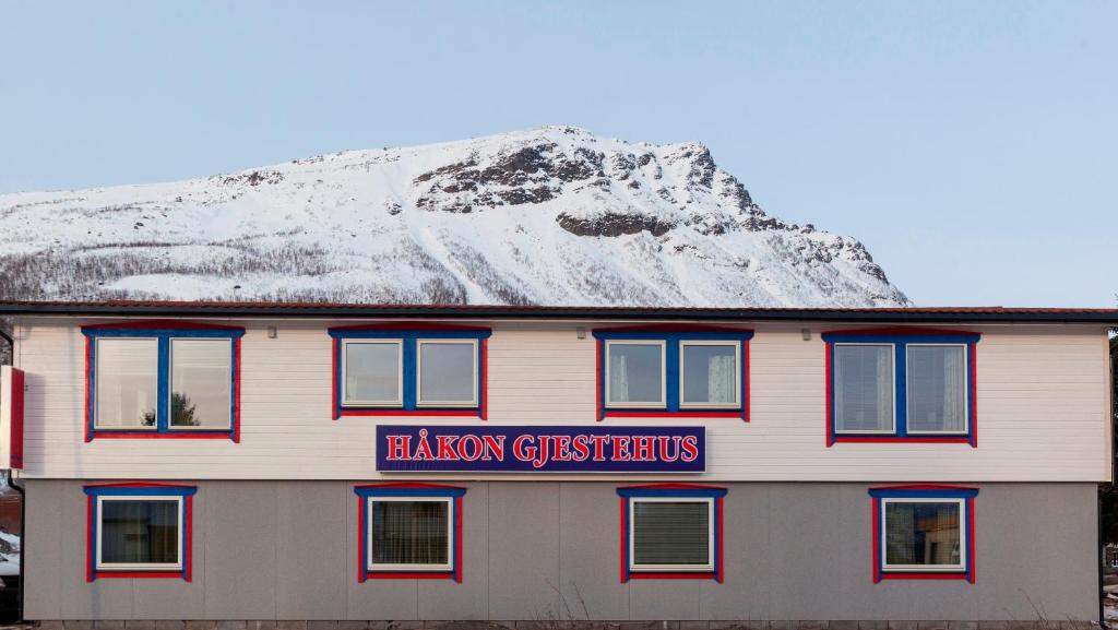 a building with a sign on it with a snow covered mountain at Håkon Gjestehus in Olderdalen