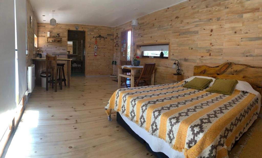 a bedroom with a bed and a wooden wall at Wau Purul, Cabaña 2 in Cholila