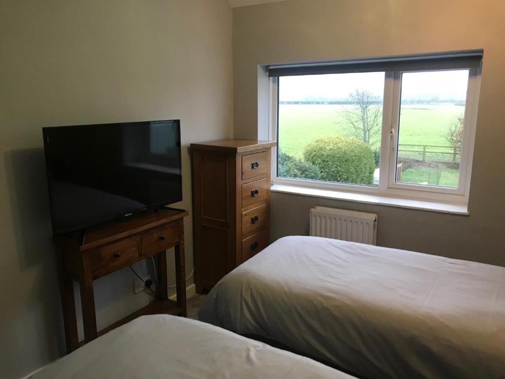 a bedroom with two beds and a flat screen tv at Cottars in Winfrith Newburgh