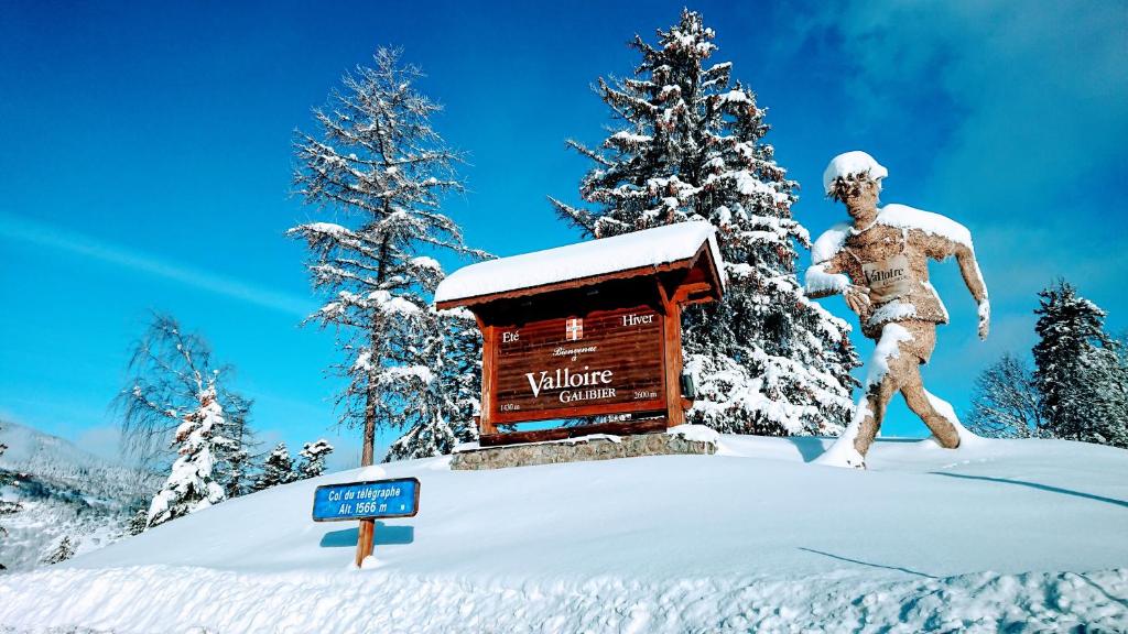 a statue of a man in the snow next to a cabin at Chalet des Plans in Valloire