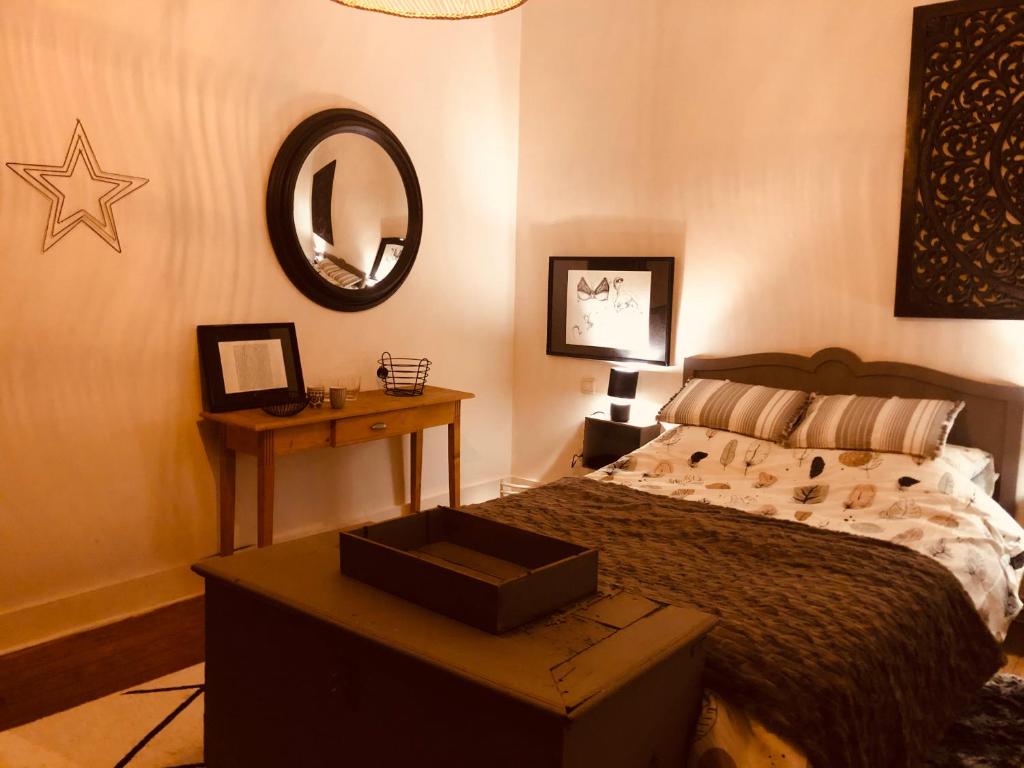 a bedroom with a bed and a mirror and a table at La mosane in Profondeville