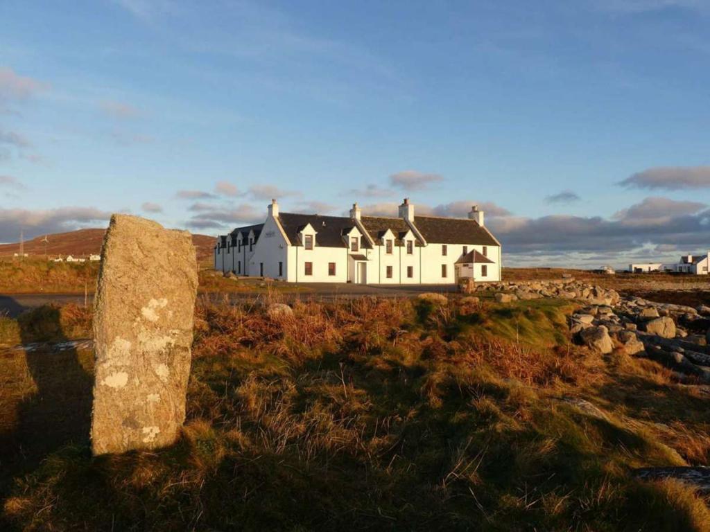 una grande casa bianca seduta in cima a un campo di Polochar Inn a Lochboisdale