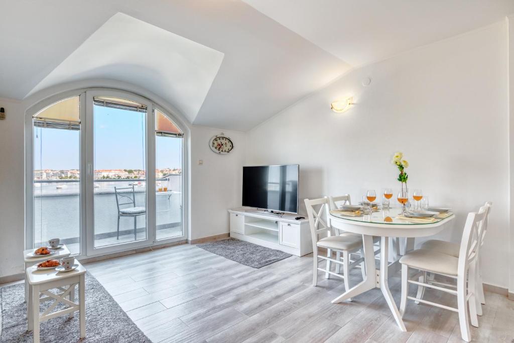 un soggiorno con tavolo, sedie e televisione di Penthouse Zola with private parking a Medulin