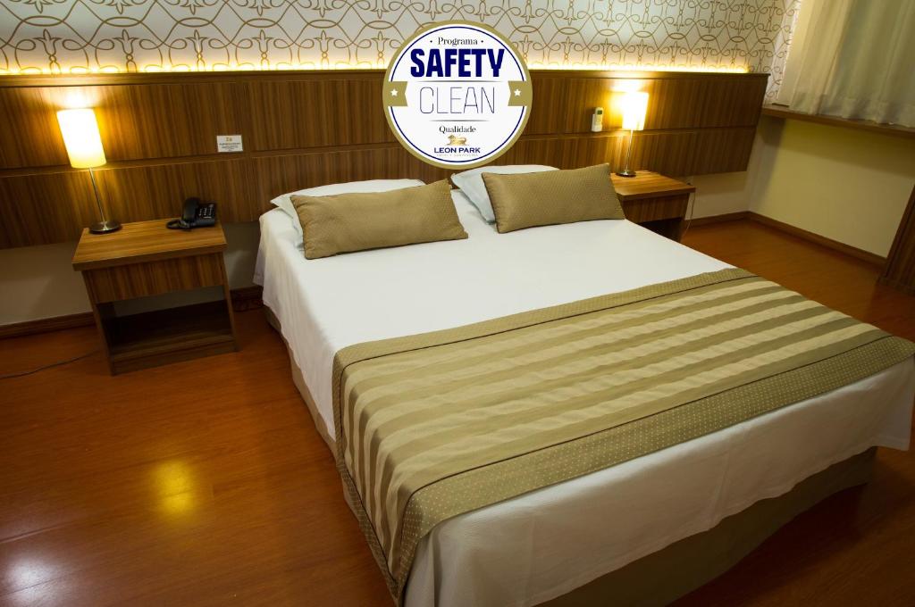 a large bed in a room with two tables at LEON PARK HOTEL e CONVENÇÕES - Melhor Custo Benefício in Campinas