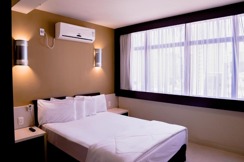 a hotel room with a bed and a window at Master Curitiba Hotel - Centro - A 2km do Batel in Curitiba