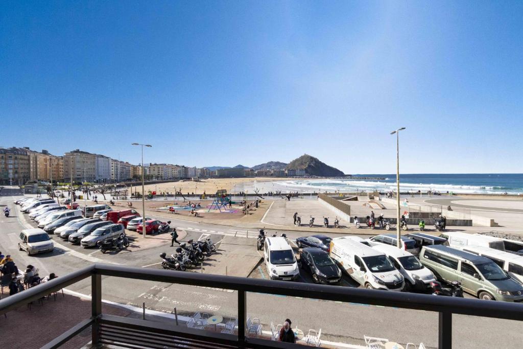 a parking lot with parked cars and a beach at The Rentals Collection - Monpas in San Sebastián