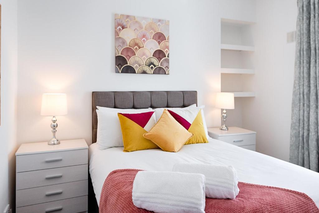 1 dormitorio con 1 cama con almohadas amarillas y rojas en STOP at this space, near the Liberty en Swansea