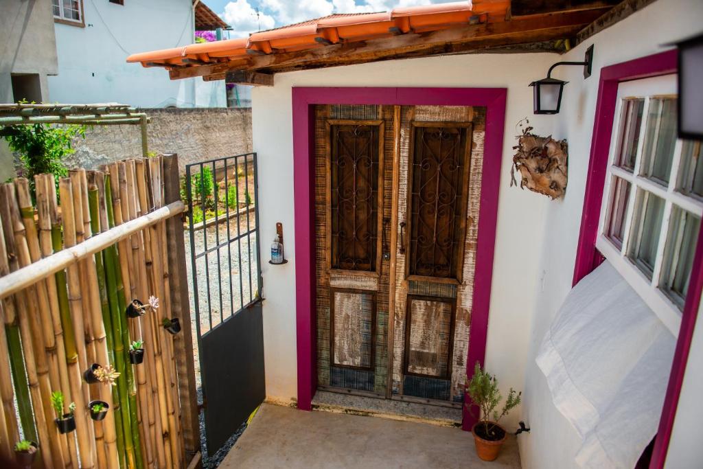 ein Haus mit einer rosa Tür und einem Zaun in der Unterkunft Aconchego de Tiradentes in Tiradentes