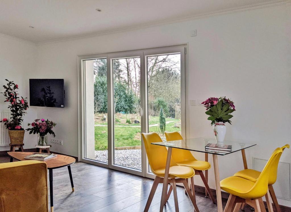 een eetkamer met een glazen tafel en gele stoelen bij Maison Blanche en Côte de Nacre in Mathieu