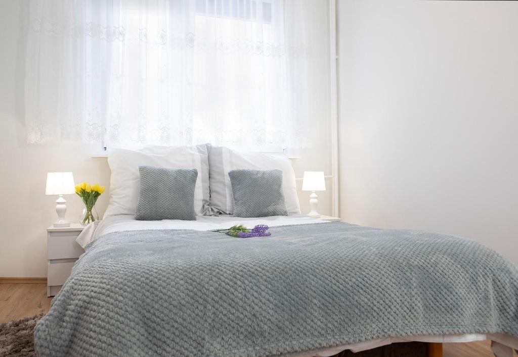 a white bedroom with a bed and a window at Luxus Apartament Alex in Gdynia