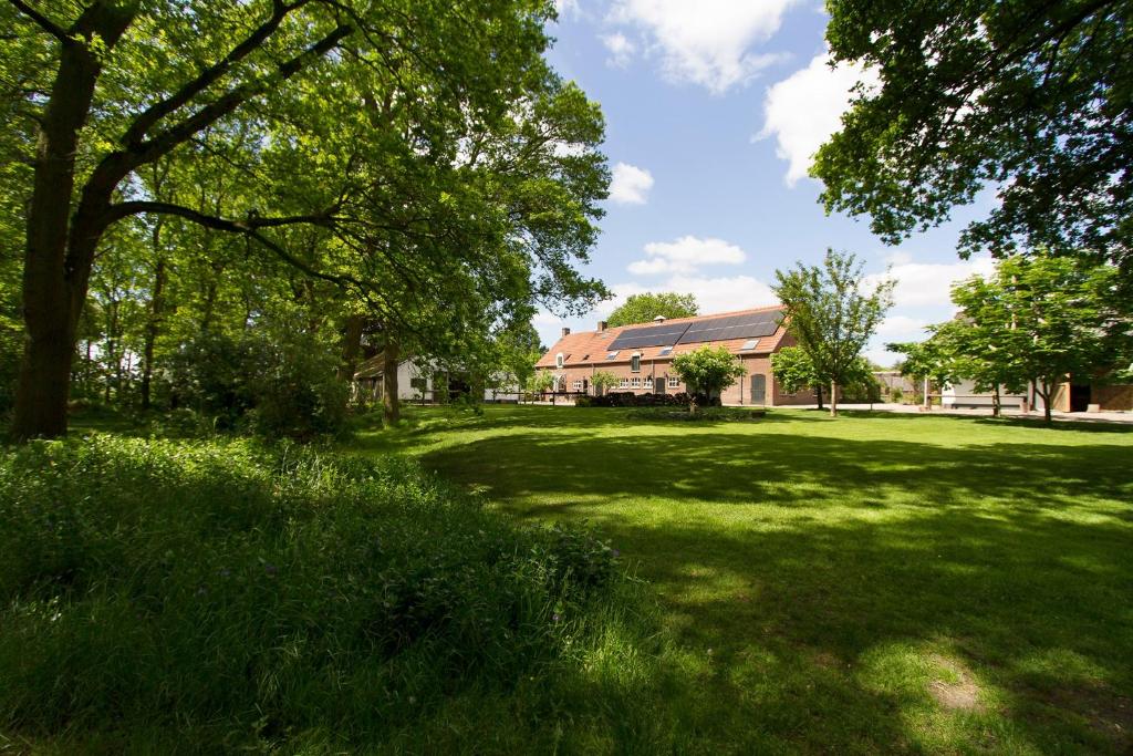 une cour verdoyante avec des arbres et une maison dans l'établissement Logies Angelbeeck, à Afferden