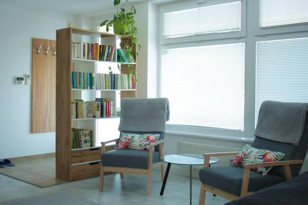 Apartmán - Dlhé Diely في براتيسلافا: غرفة معيشة مع كرسيين ورف كتاب