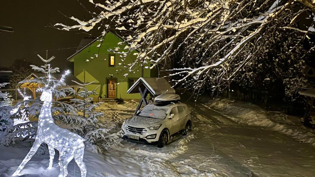 ein Auto, das auf einem schneebedeckten Hof mit einer Giraffe parkt in der Unterkunft Goryanka family home in Mykulytschyn
