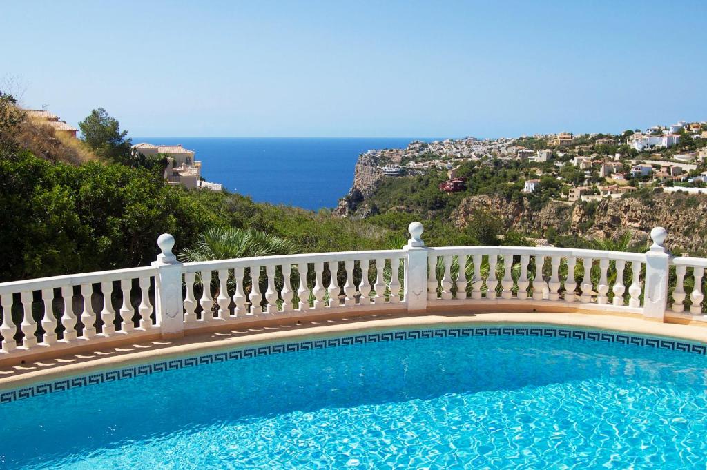een zwembad met een wit hek en de oceaan bij CASA VIDA, villa encantadora con vistas al mar in Benitachell