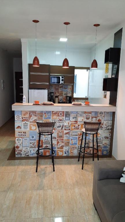 a kitchen with a counter with two bar stools at Apartamento mobiliado com varanda no centro de paulo afonso in Paulo Afonso