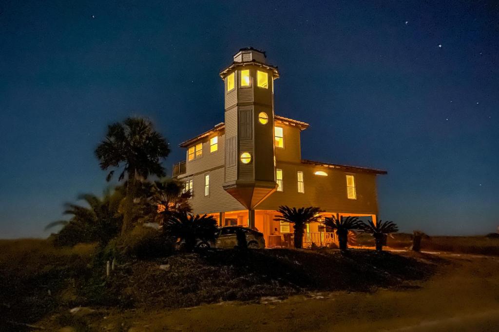 um grande edifício com uma torre de relógio à noite em Lighthouse By The Sea em St. George Island