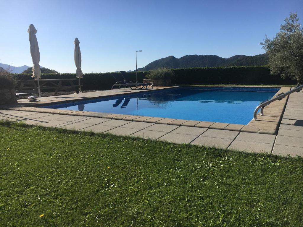 a swimming pool with umbrellas in a yard at Apartaments Cal Borda in Coll de Nargó