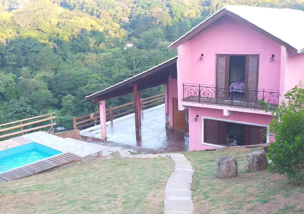 a pink house with a balcony and a swimming pool at Casa em São Roque Com belissima vista. in São Roque