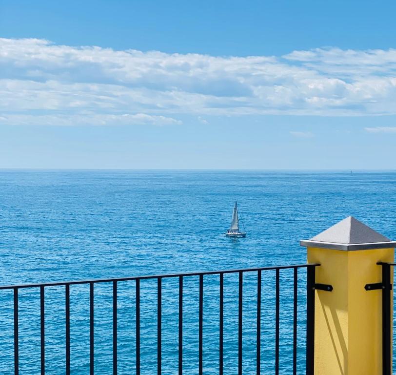 un bateau dans l'océan avec un voilier dans l'établissement La Polena Camere Vernazza - Suite vista mare, à Vernazza