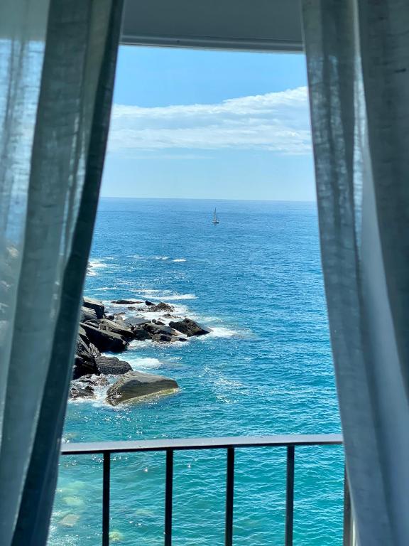 a view of the ocean from a balcony with a boat in the water at La Polena Camere Vernazza - Suite vista mare in Vernazza