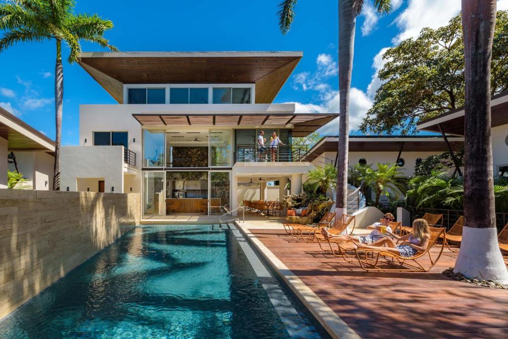 a house with a swimming pool and palm trees at Mother Earth Luxury Boutique Hotel, Restaurant & Spa in Tamarindo