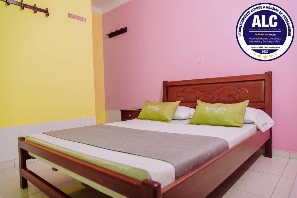 Cama en habitación con paredes de color rosa y amarillo en Ayenda 1615 Hotel Tayrona Mágico, en Santa Marta