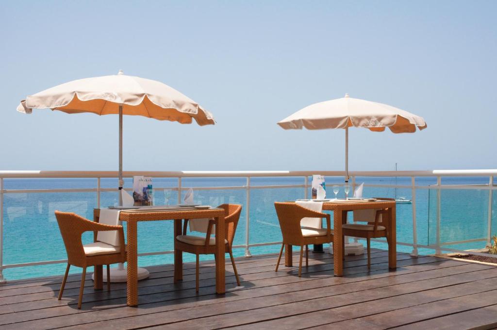 two tables and chairs with umbrellas on a deck at XQ El Palacete in Morro del Jable