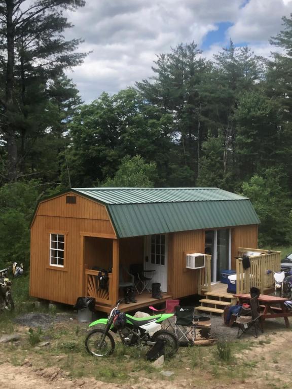 una pequeña cabaña con una motocicleta estacionada frente a ella en The HideAway Tiny Cabin en East Durham