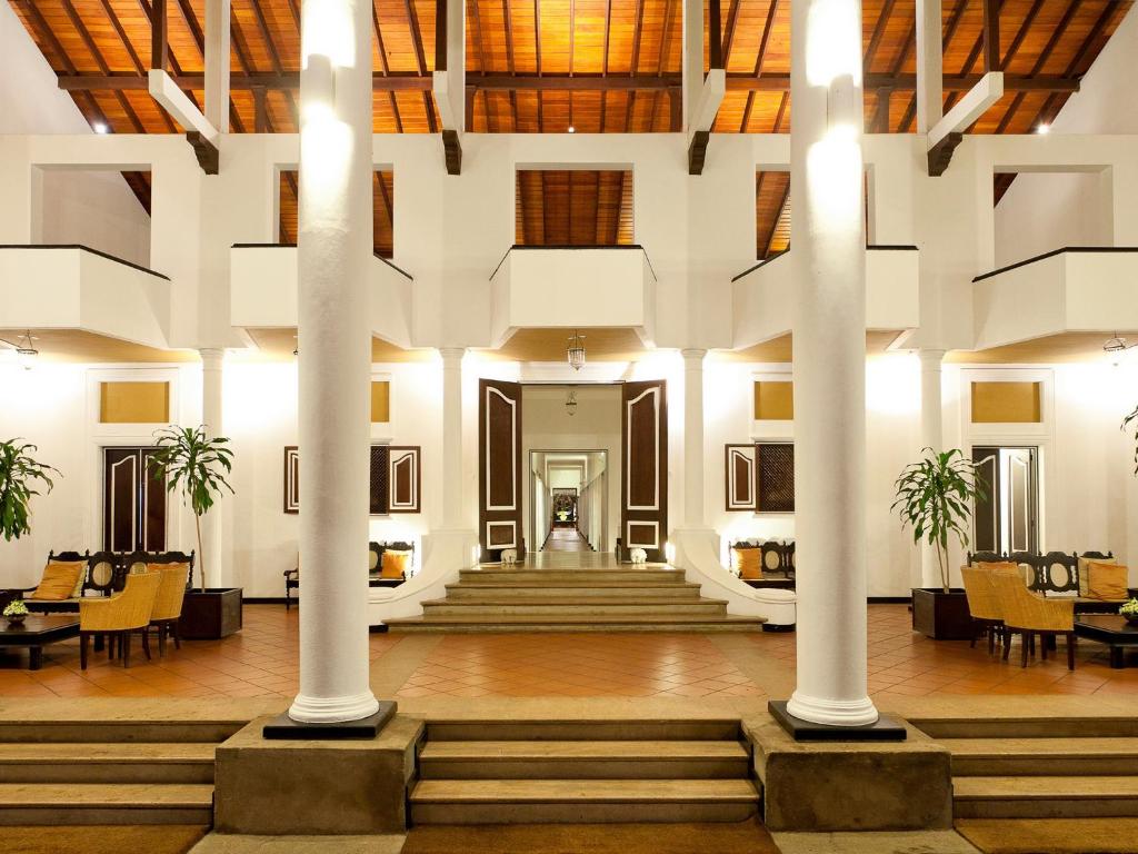 a lobby with white columns and tables and chairs at Cinnamon Lodge Habarana in Habarana