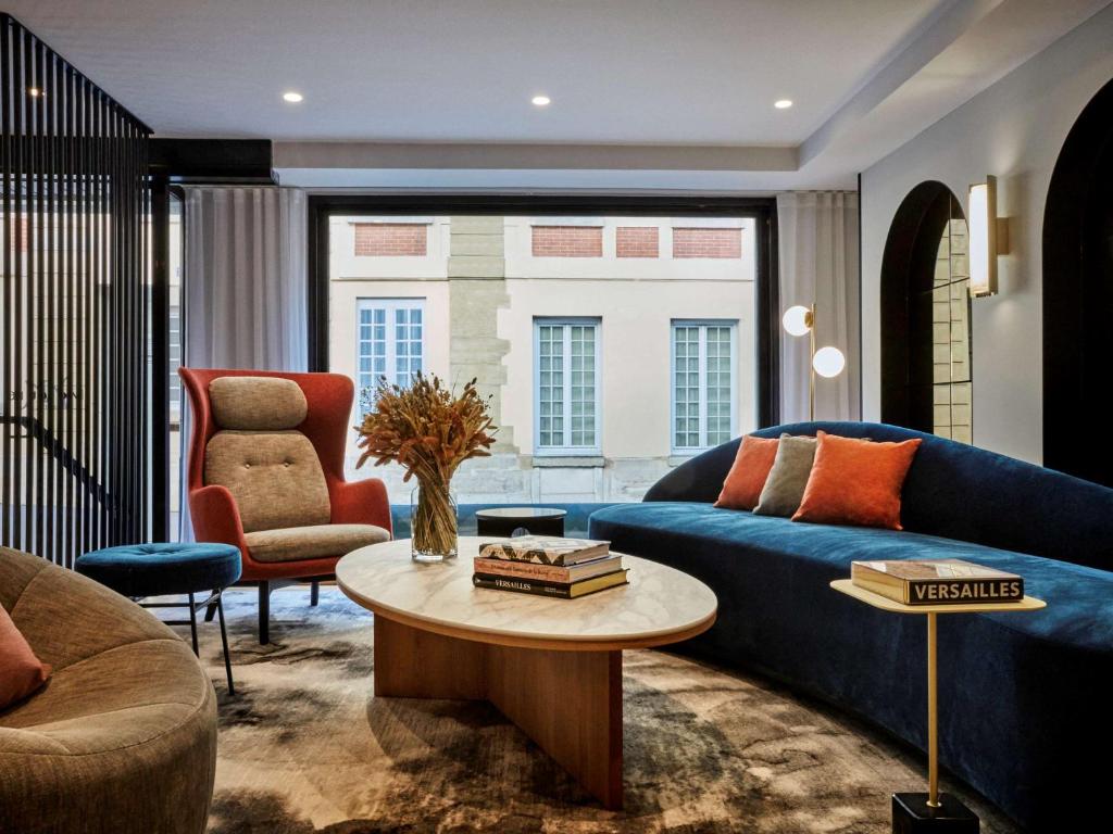 a living room with a blue couch and a table at Mercure Versailles Chateau in Versailles