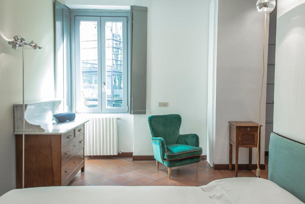 ein Schlafzimmer mit einem Bett, einem Stuhl und einem Fenster in der Unterkunft Brera Apartments in Porta Romana in Mailand