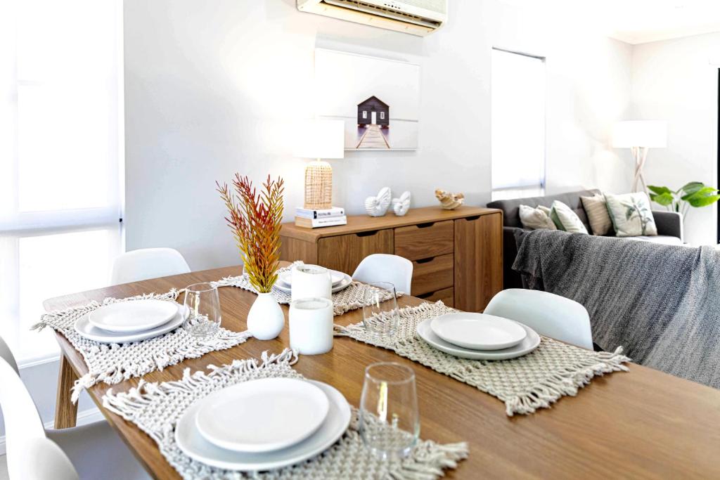 a dining room table with white plates and chairs at Paradise Palms CLOSE TO BEACH, WIFI, 2 BEDROOMS in Airlie Beach