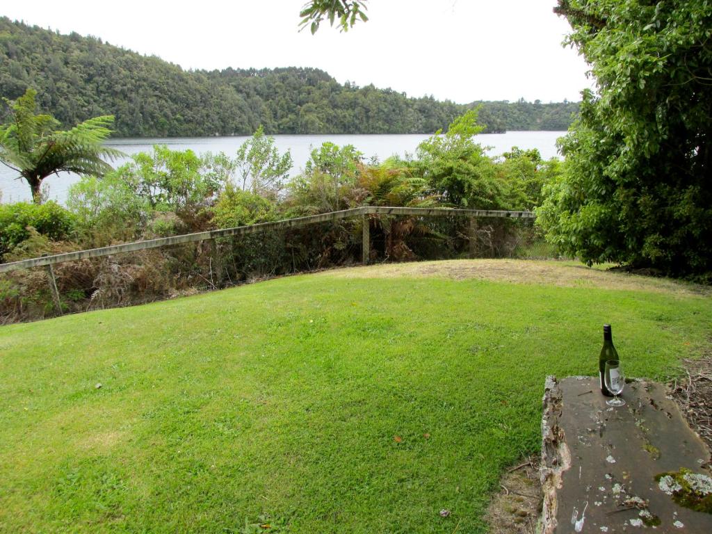 Rotoiti的住宿－Lake Rotoehu Accommodation - Lake Rotoehu Home，坐在一块岩石上,坐在那里,喝一瓶葡萄酒