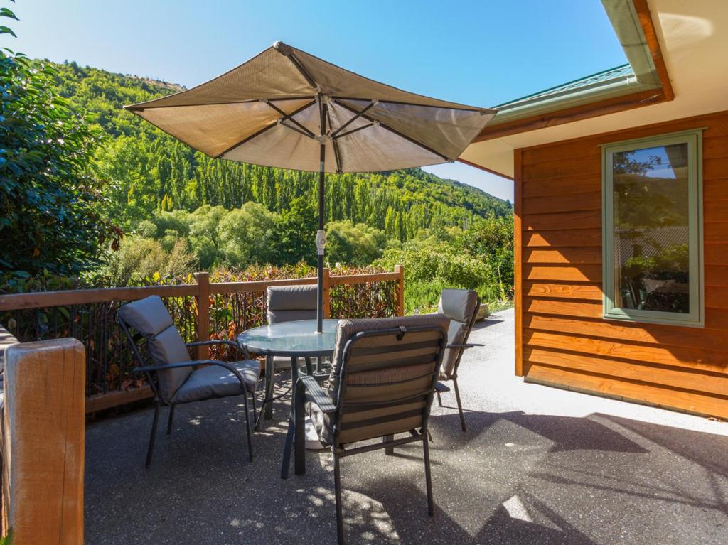 a patio with a table and chairs and an umbrella at Sawmillers Retreat - Arrowtown Holiday Home in Arrowtown