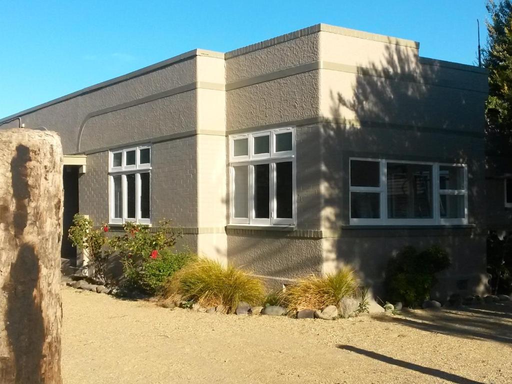 a gray house with white windows and plants at Ezy Walk - Blenheim Holiday Home in Blenheim