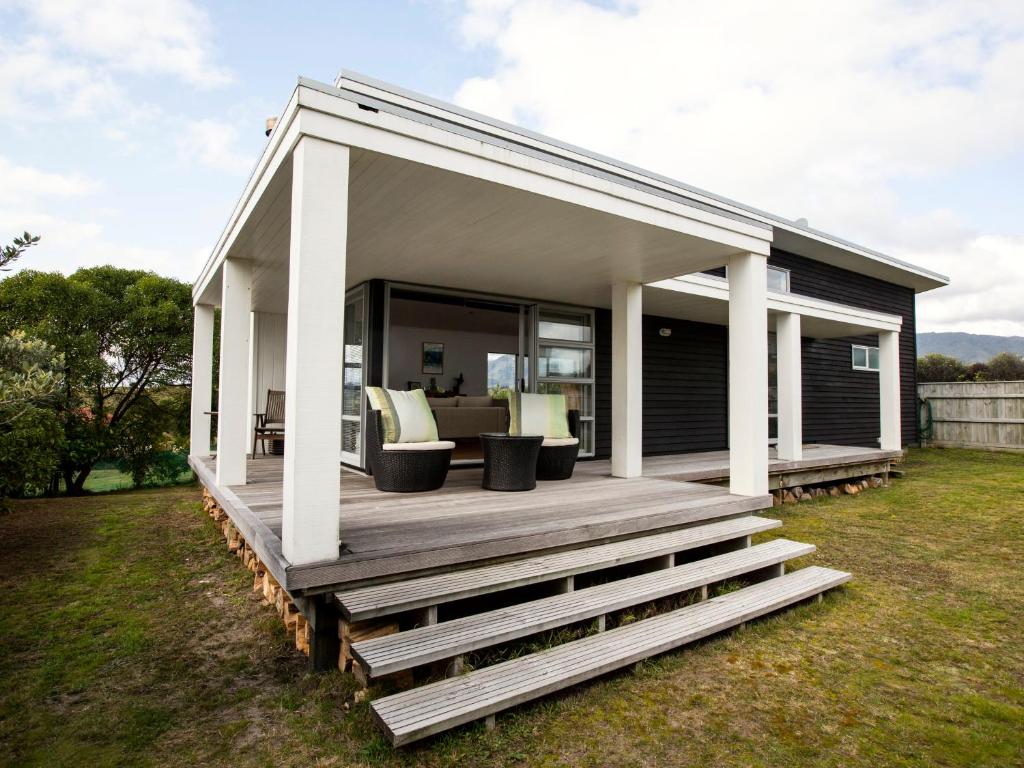 une petite maison avec un porche et une terrasse dans l'établissement Waikanae Retreat - Waikanae Beach Holiday Home, à Waikanae
