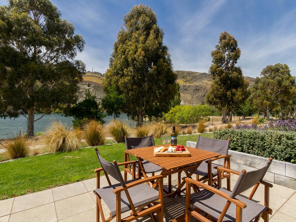 a wooden table with chairs and a bottle of wine at Sunhaven Lakeside - Cromwell Holiday Home in Cromwell