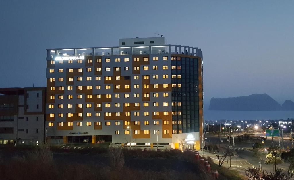 un edificio alto con muchas ventanas por la noche en Grandmillions Hotel Seogwipo en Seogwipo