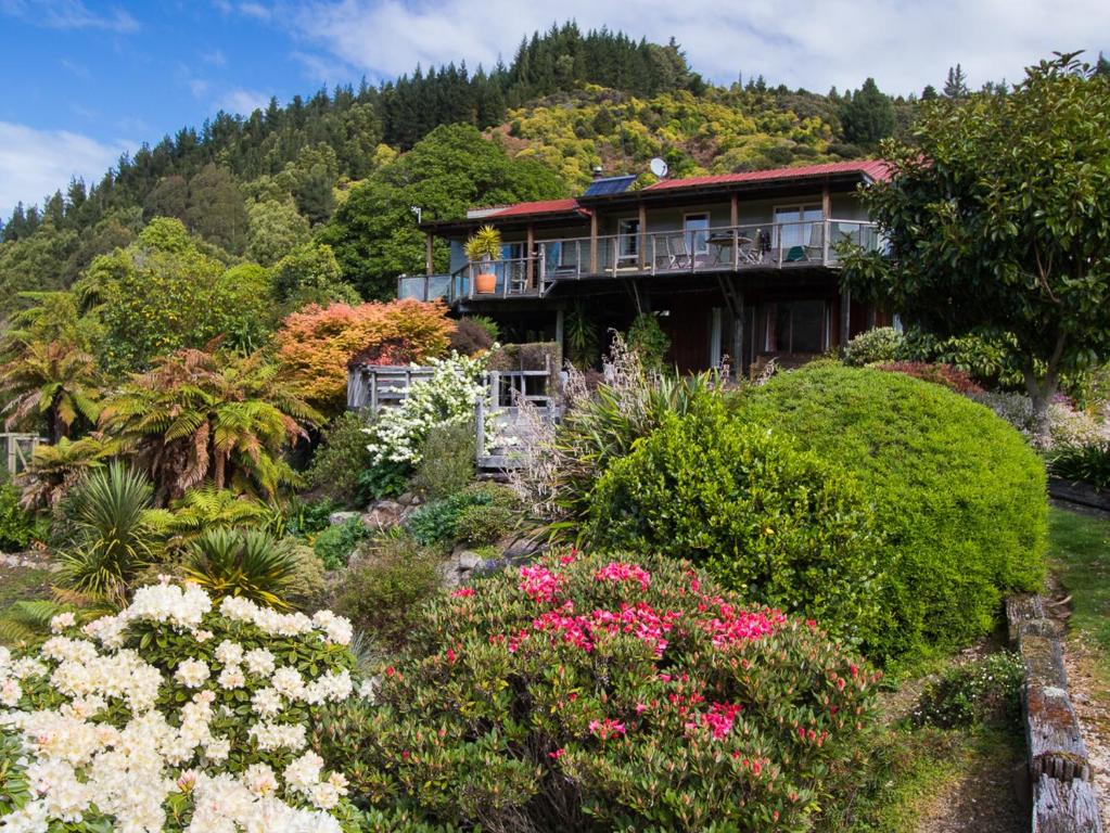 uma casa no topo de uma colina com flores em Tasman Hideaway - Marahau Holiday Home em Marahau