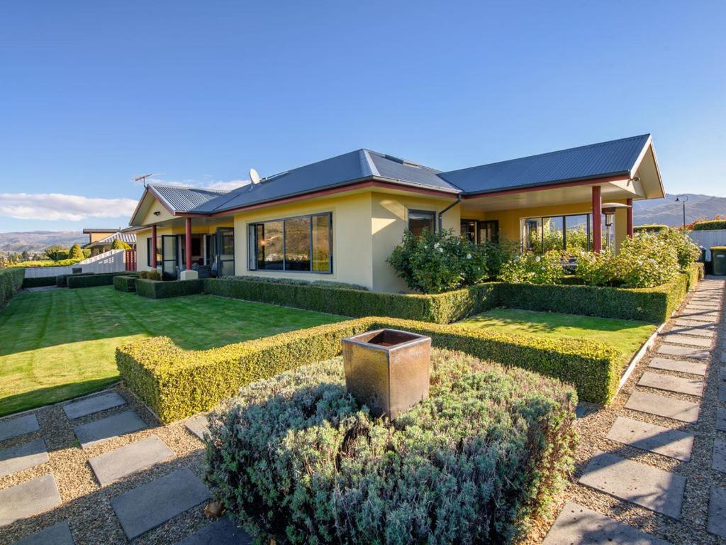 a house with hedges in front of a yard at Kawarau Bay View - Cromwell Holiday Home in Cromwell