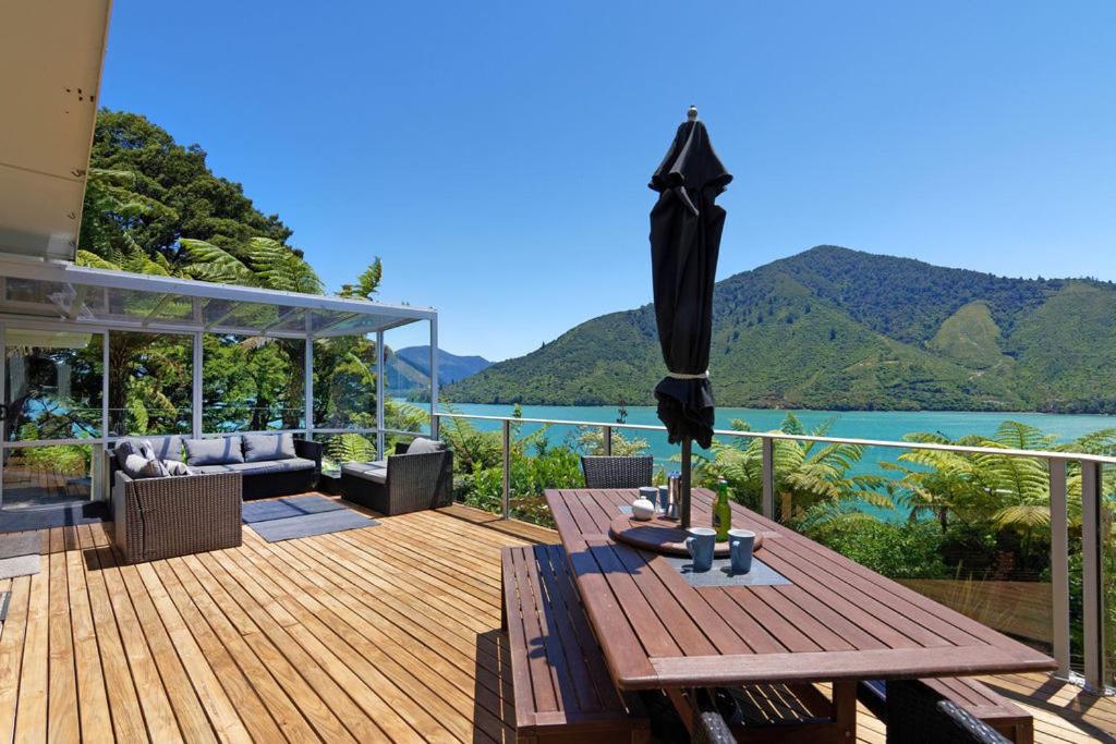 Whatanihi的住宿－Aquamarine Dreams - Marlborough Holiday Home，木甲板配有桌子和遮阳伞