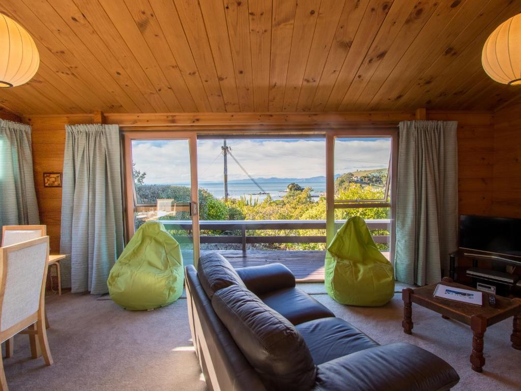 a living room with a couch and a large window at Beach House on the Ridge - Kaiteriteri House in Kaiteriteri