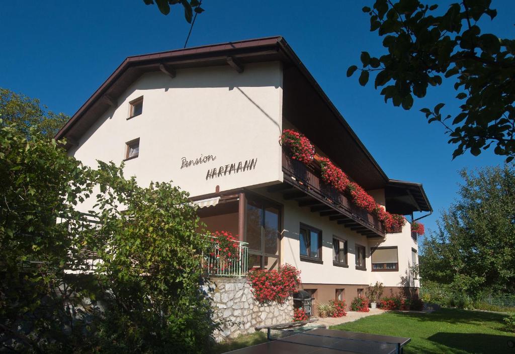 - un bâtiment blanc avec des fleurs sur le balcon dans l'établissement Pension Hartmann, à Sankt Kanzian